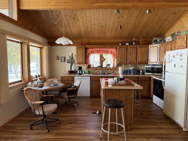 kitchen with white appliances, a center island, vaulted ceiling, light countertops, and a sink