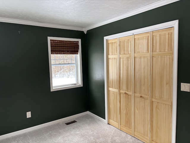 unfurnished bedroom with baseboards, crown molding, visible vents, and carpet flooring