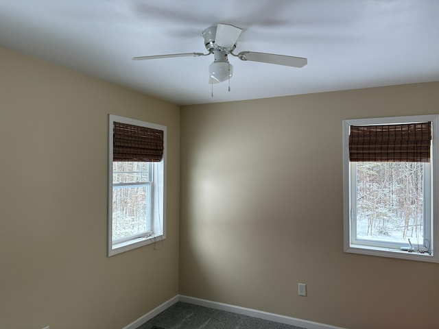 empty room with ceiling fan, baseboards, and dark carpet