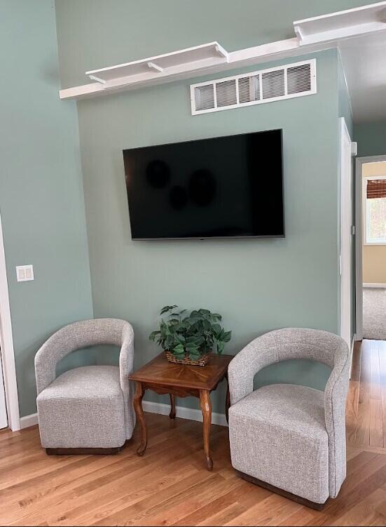 sitting room featuring wood finished floors, visible vents, and baseboards