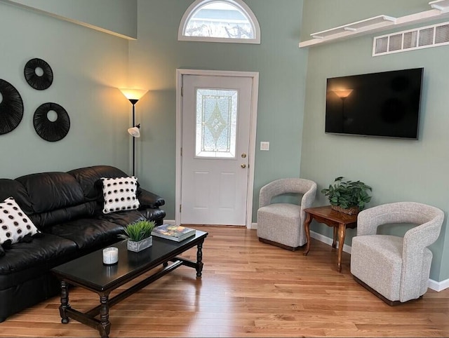 living room featuring light wood finished floors, plenty of natural light, visible vents, and baseboards