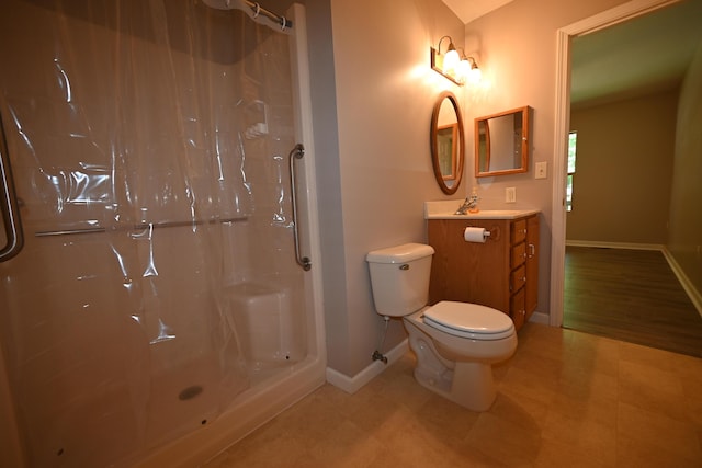 bathroom featuring toilet, walk in shower, vanity, and baseboards