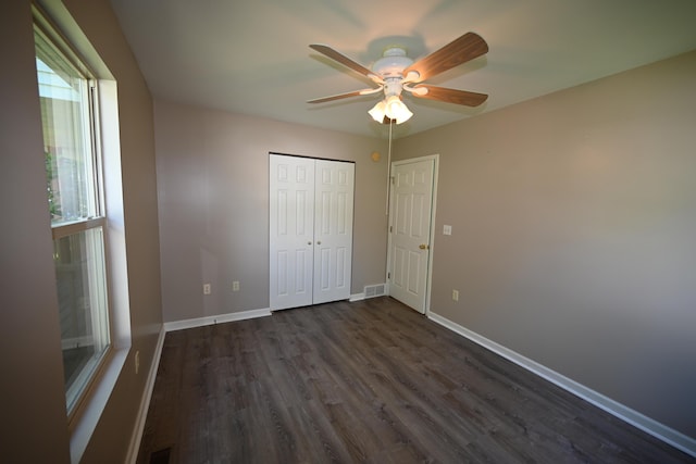 unfurnished bedroom with dark wood-type flooring, a closet, visible vents, and baseboards