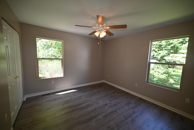 unfurnished room featuring dark wood finished floors, baseboards, and ceiling fan