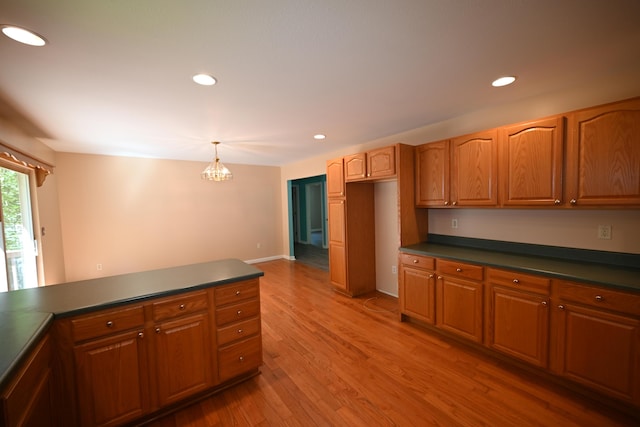 kitchen featuring pendant lighting, light wood-style floors, dark countertops, and brown cabinets