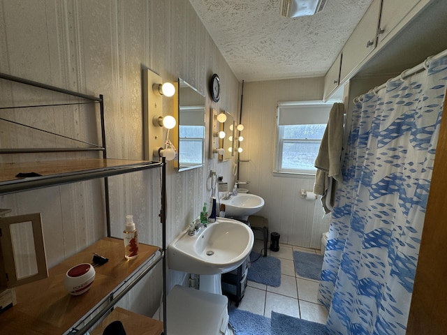 bathroom featuring a sink, a shower with curtain, tile patterned flooring, and a textured ceiling