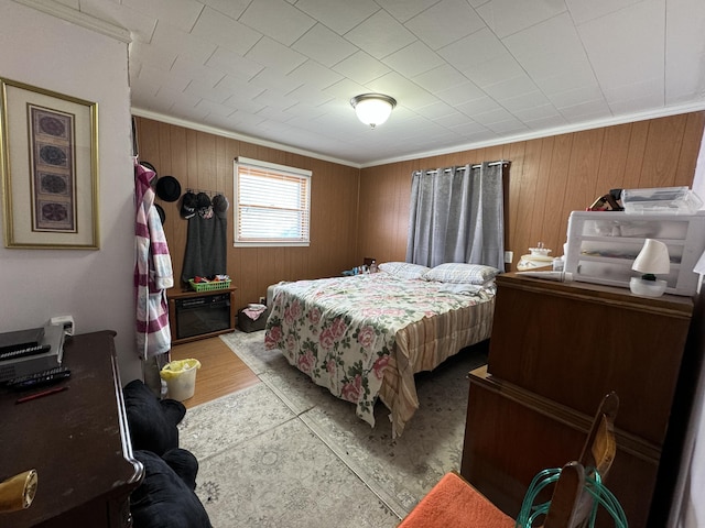 bedroom featuring wood walls, ornamental molding, and light wood-style floors