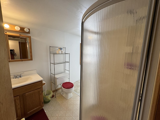 bathroom featuring toilet, a shower with shower door, and vanity