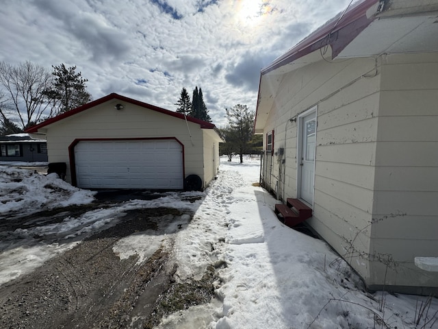 snow covered property with a garage and an outdoor structure