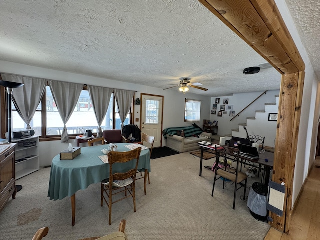 dining space with ceiling fan, a textured ceiling, and stairs