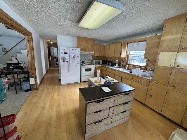 kitchen featuring a textured ceiling, under cabinet range hood, white appliances, a sink, and light wood-type flooring