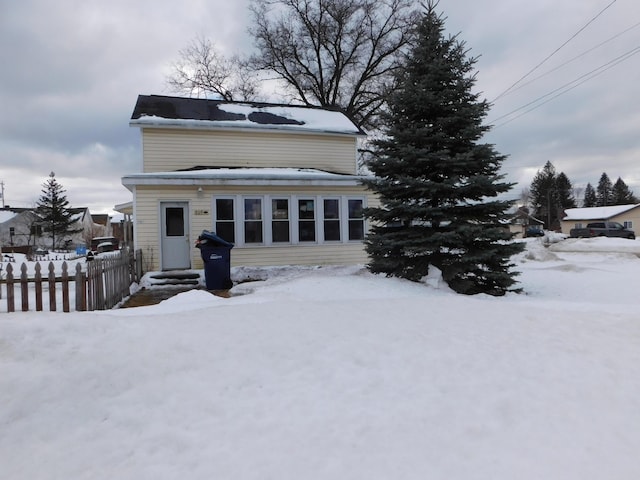 snow covered rear of property featuring entry steps and fence