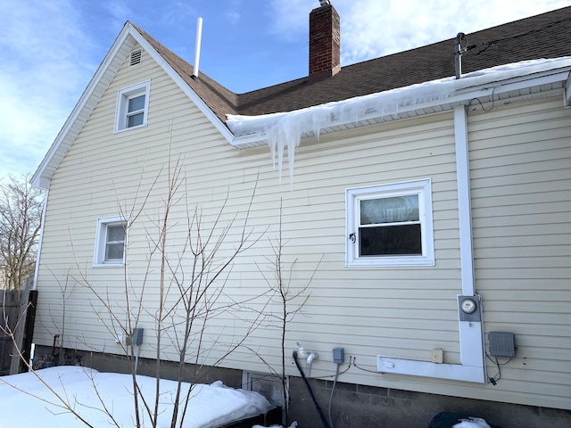 view of home's exterior featuring roof with shingles and a chimney