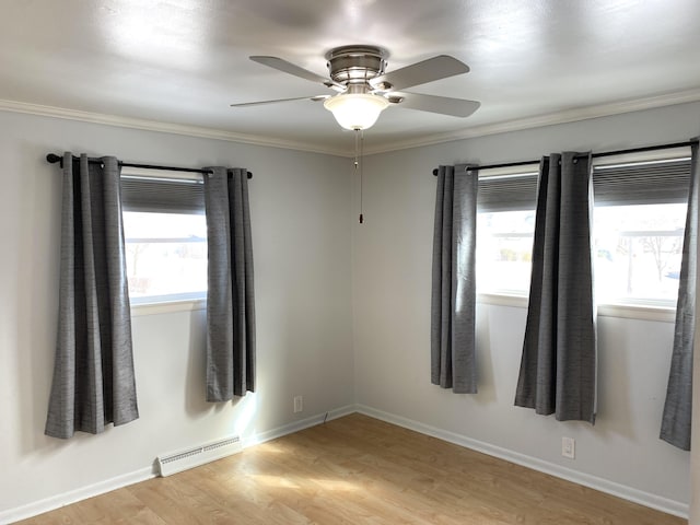 spare room featuring baseboards, a ceiling fan, crown molding, light wood-type flooring, and a baseboard heating unit