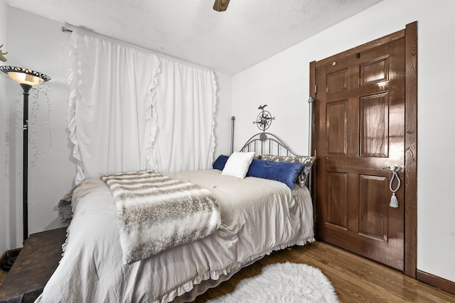 bedroom with ceiling fan, a textured ceiling, and wood finished floors