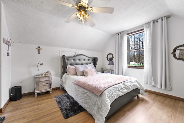 bedroom with lofted ceiling, a textured ceiling, baseboards, and wood finished floors