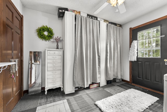 entrance foyer with a textured ceiling, ceiling fan, carpet flooring, and baseboards