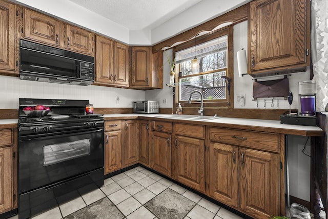 kitchen with black appliances, light tile patterned floors, brown cabinetry, and a sink