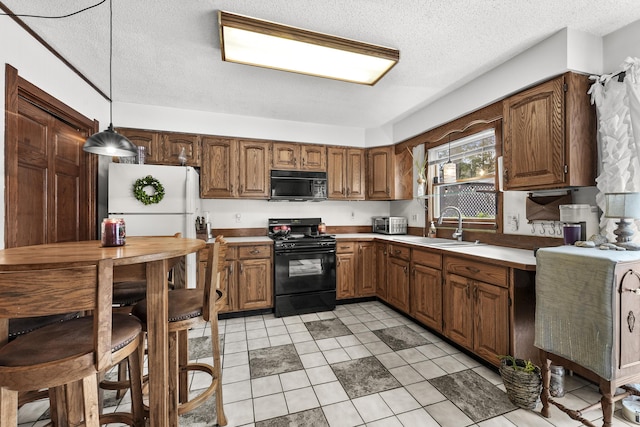 kitchen featuring hanging light fixtures, black appliances, brown cabinets, and a sink