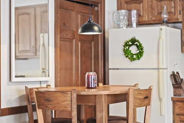 interior space featuring freestanding refrigerator and hanging light fixtures