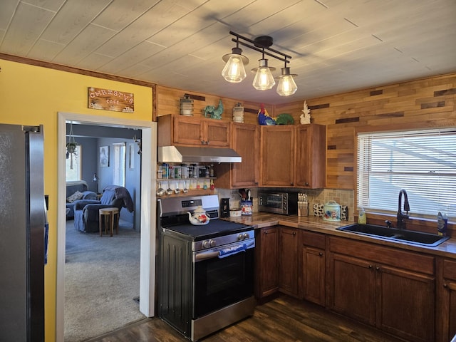 kitchen featuring tasteful backsplash, brown cabinets, stainless steel appliances, under cabinet range hood, and a sink