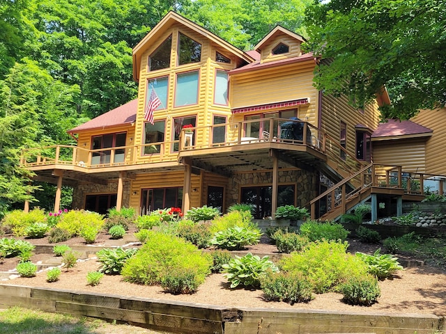 rear view of house featuring stone siding, a wooden deck, and stairs