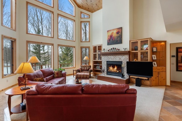 living room with high vaulted ceiling, a tile fireplace, wooden ceiling, and baseboards