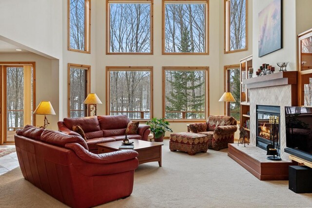 carpeted living area featuring a glass covered fireplace and a towering ceiling