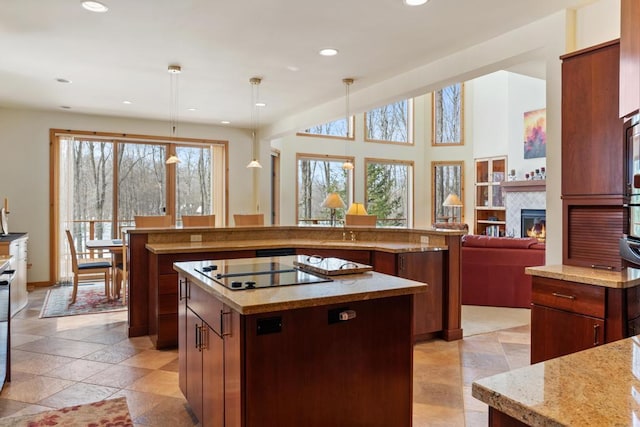 kitchen featuring a glass covered fireplace, a spacious island, black electric cooktop, pendant lighting, and recessed lighting