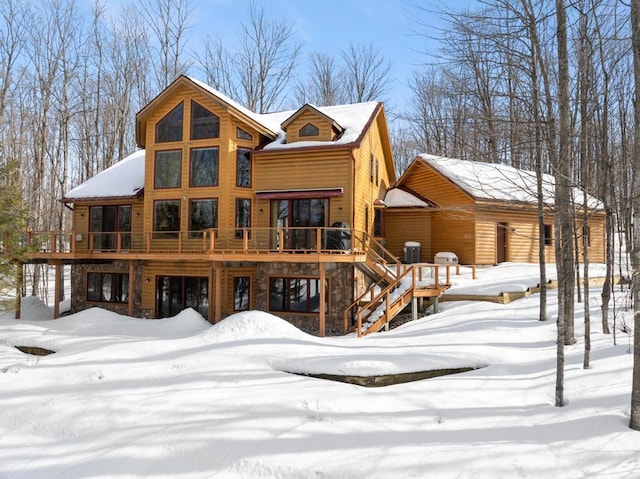 rear view of house with a deck, stone siding, stairway, and a garage