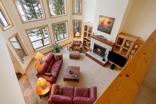 living room with a towering ceiling, carpet floors, and a tiled fireplace