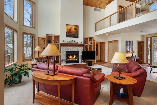 living room with carpet, a high ceiling, a tiled fireplace, and visible vents