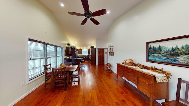 dining area featuring a ceiling fan, a barn door, high vaulted ceiling, and hardwood / wood-style floors