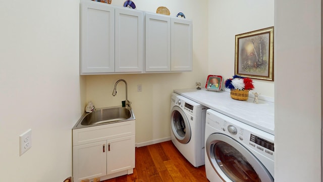 laundry area with wood finished floors, washing machine and clothes dryer, a sink, and cabinet space