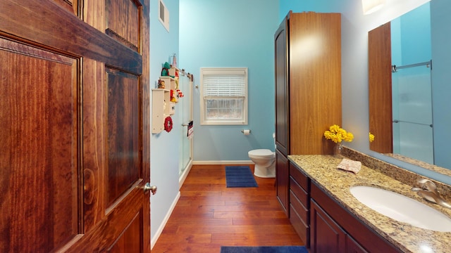 bathroom with baseboards, visible vents, toilet, hardwood / wood-style flooring, and vanity