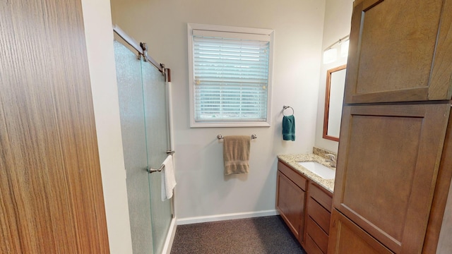 full bath featuring a stall shower, vanity, and baseboards