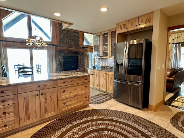 kitchen featuring decorative backsplash, stainless steel fridge with ice dispenser, glass insert cabinets, an inviting chandelier, and light brown cabinets