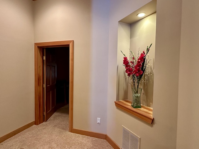 hall featuring baseboards, visible vents, and carpet flooring