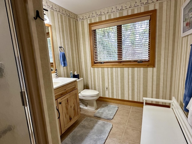 bathroom featuring toilet, wallpapered walls, tile patterned flooring, and baseboards