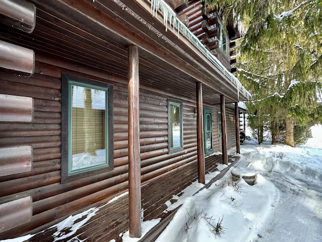 snow covered property with faux log siding