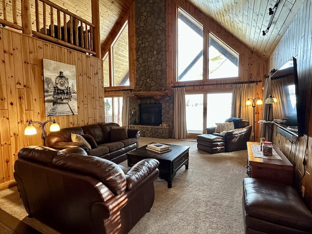 living area with wooden ceiling, wood walls, carpet, and a stone fireplace