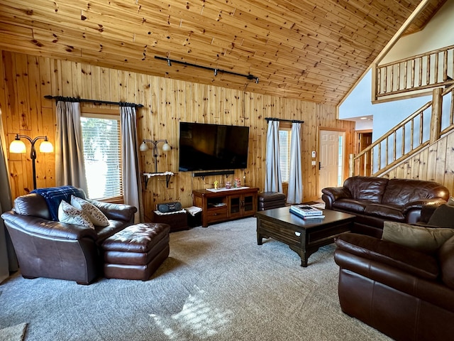 carpeted living room with rail lighting, wood walls, high vaulted ceiling, wooden ceiling, and stairs