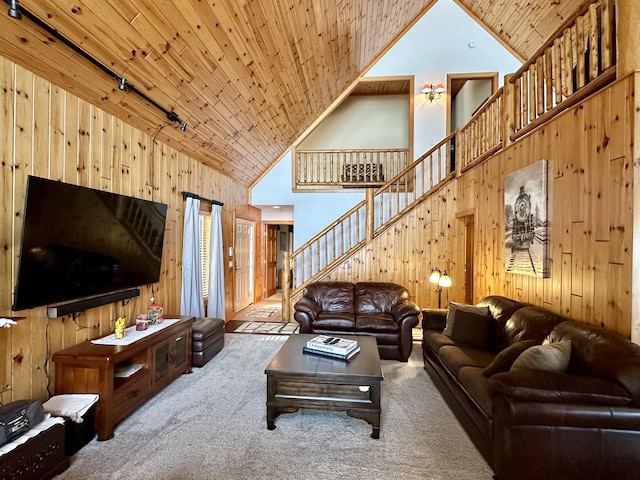 living room with high vaulted ceiling, wooden ceiling, wooden walls, carpet flooring, and stairway