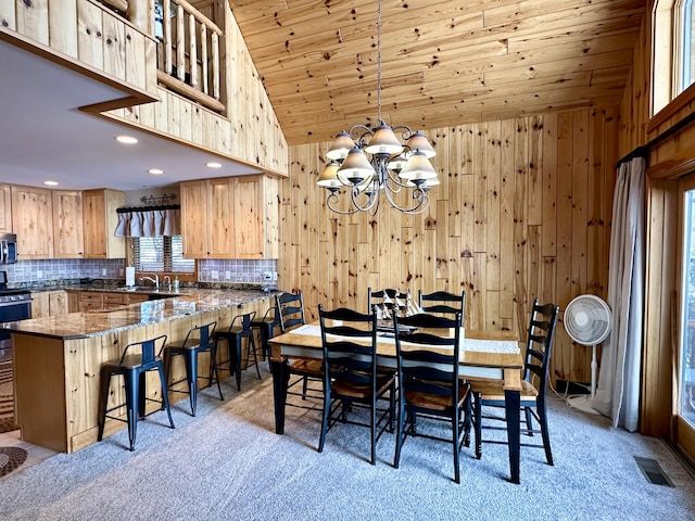 dining space with wood ceiling, visible vents, wood walls, and light carpet