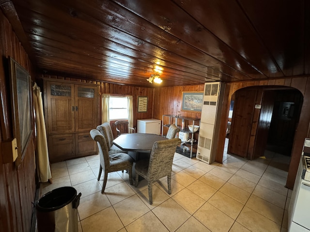 dining area with wooden ceiling, light tile patterned floors, arched walkways, and wood walls