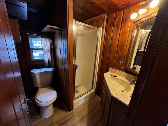 bathroom with toilet, wood walls, a shower stall, and vanity