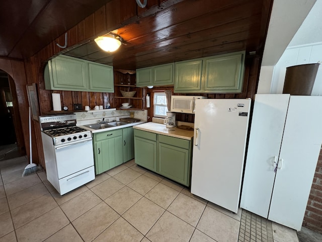 kitchen featuring light tile patterned floors, open shelves, green cabinets, a sink, and white appliances