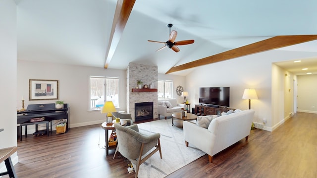 living room with vaulted ceiling with beams, a stone fireplace, wood finished floors, a ceiling fan, and baseboards