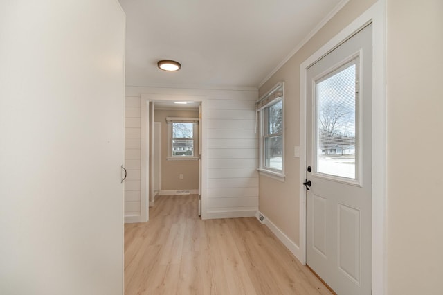 doorway featuring light wood finished floors, baseboards, and crown molding