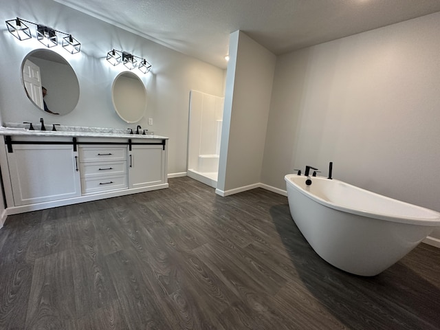 bathroom featuring double vanity, a soaking tub, a sink, wood finished floors, and walk in shower